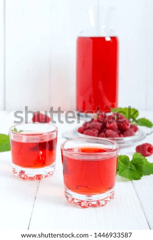 Raspberry liqueur in glass and fresh berries on a white background. Alcoholic flavored drink.