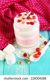 Raspberry milk dessert in glass jar, on color wooden background