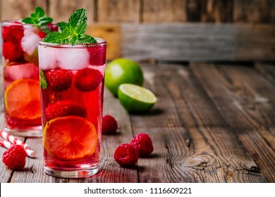 Raspberry Mojito Lemonade with lime and fresh mint in glass on wooden background. Summer refreshing cocktail. 