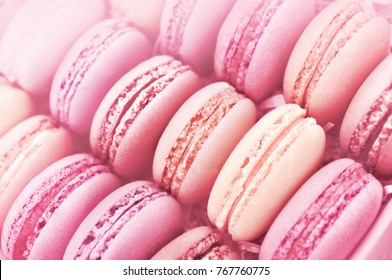 Raspberry and strawberry pink macarons on soft pastel pink background, shallow DOF, toned