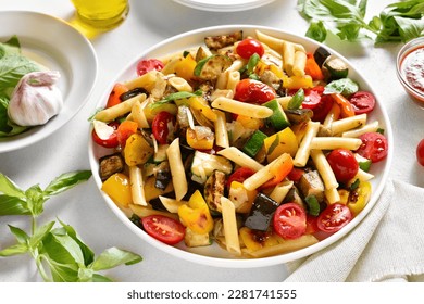Ratatouille pasta salad on plate over white stone background. Close up view