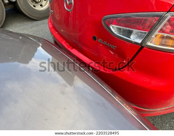 Ratchaburi, Thailand , 2 September 2022 : a car bumped\
the back of a red mazda 2 and got dented on the back of the car on\
the road 