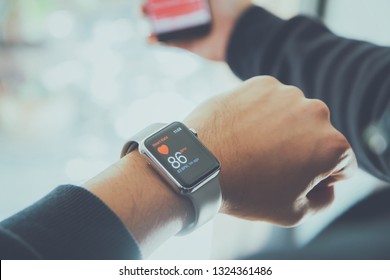 RATCHABURI, THAILAND - AUGUST 19, 2017: Asian Athletes Man Resting After Exercising. And Use A Smartphone And Apple Watch With Check Health Data.