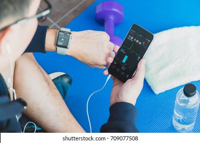 RATCHABURI, THAILAND - AUGUST 19, 2017: Asian Athletes Man Resting After Exercising. Uses A Smartphone And Apple Watch With Headphones To Listen To Music.