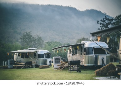 Ratchaburi / Thailand - Jan 22, 2018: Caravan camping campsite of American Airstream travel trailers parking in the yard in the morning with mountain and fog in the background.