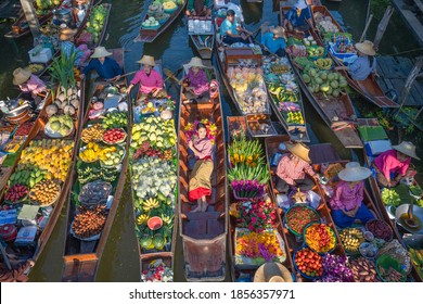 Ratchaburi, Thailand - November 15, 2020 : Peoples sell Thai cuisine on wooden boat at Damnoen Saduak Floating Market the tourists visiting by boat is popular tourist attraction on canals of Thailand.
