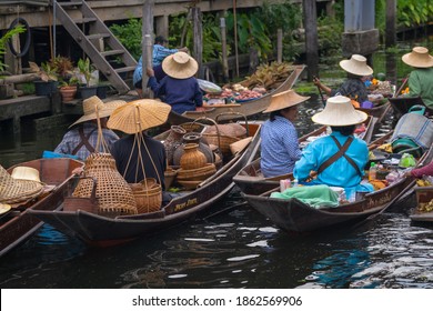 Ratchaburi, Thailand - September 18, 2020 : Peoples sell Thai cuisine on wooden boat at Damnoen Saduak Floating Market the tourists visiting by boat is popular tourist attraction on canal of Thailand.