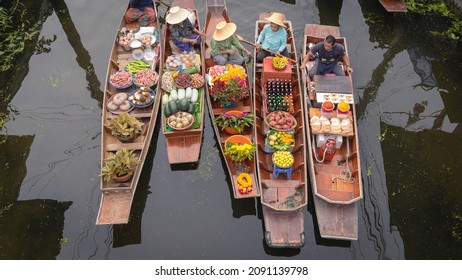 Ratchaburi, Thailand - September 18, 2020: Peoples sell Thai cuisine on wooden boat at Damnoen Saduak Floating Market the tourists visiting by boat popular tourist attraction on canals of Thailand.
