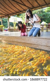 Ratchaburi,Thailand - NOVEMBER 24 2020:  Mother and child feeding koi fish in Ratchaburi,the cute little boy has fun with family on the weekend.