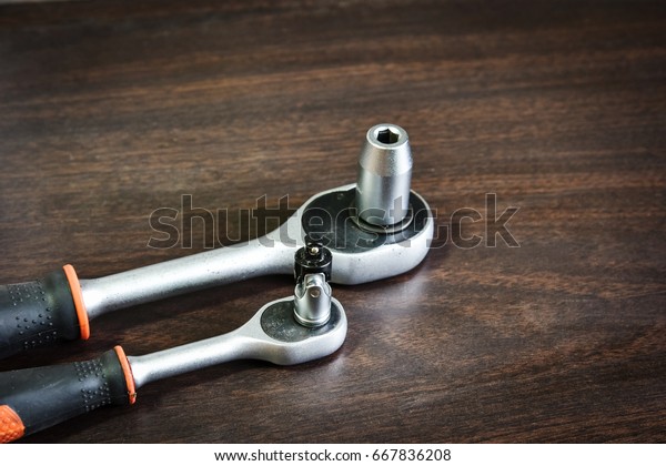 ratchet (socket) wrench lying on wooden background\
with copy space for\
text