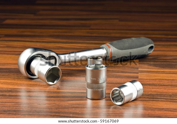 Ratchet spanner\
and sockets on wood\
background
