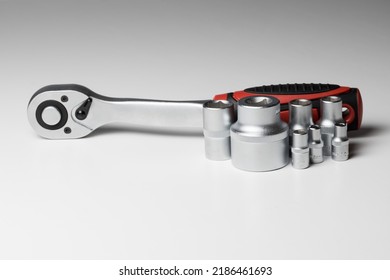Ratchet wrench with hex socket and several interchangeable sockets of different sizes on a white surface. High quality photo