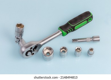 Ratchet wrench with hexagonal socket which was inserted via a gimbal joint adapter, extension adapter and several interchangeable sockets different sizes on a blue surface 