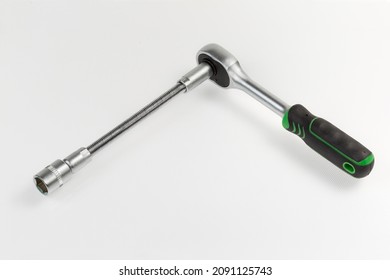 Ratchet wrench with rubberized handle with hexagonal socket which inserted via a long flexible adapter lies on a light surface