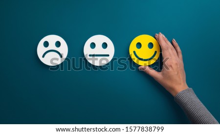 Rating concept. Woman choosing happy smile face emotion on blue background, panorama, copy space