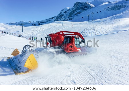 Ratrack machine making ski piste at Hintertux Glacier ski resort in Zillertal in Tyrol in Austria in winter in Alps. Alpine mountains with snow. Ratrac in Downhill. Blue sky and white slopes.