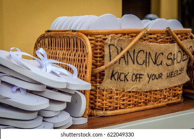 Rattan Basket With White Flip-flops Of Different Sizes For Guests, With A Writing DANCING SHOES. KICK OFF YOUR HEELS!  