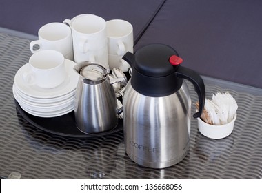 A Rattan Table With A Tray Of Empty Cups, Saucers, Coffee Pot And Sugar