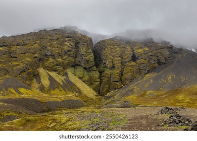 Raudfeldsgja Gorge foggy landscape with vertical cliffs covered with moss and a narrow crack, tourists walking on a trail, Botnsfjall Mountain, Snaefellsnes peninsula, Iceland.  - Powered by Shutterstock