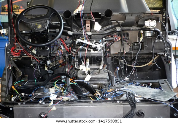 A lot of ravel multicolored wires from the car\
wiring lies in the cabin of dismantled car with connectors and\
plugs, a view through the window inside the battered car. Auto\
service industry