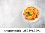 Ravioli with ricotta cheese, fresh tomato sauce and fresh basil on a gray background. Top view. Copy space