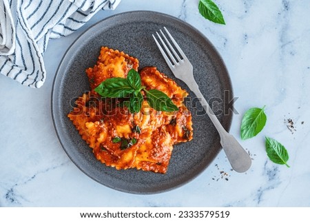 Ravioli with ricotta, tomato sauce and basil, white marble background, top view.