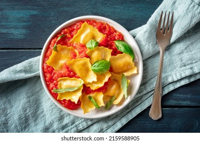 Ravioli With Tomato Sauce And Fresh Basil Leaves On A Plate, Overhead Flat Lay Shot On A Dark Rustic Wooden Background