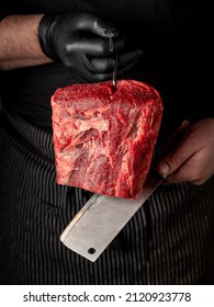 Raw aged beef steak marbled meat in chef butcher's hands with knife on black background - Shutterstock ID 2120923778
