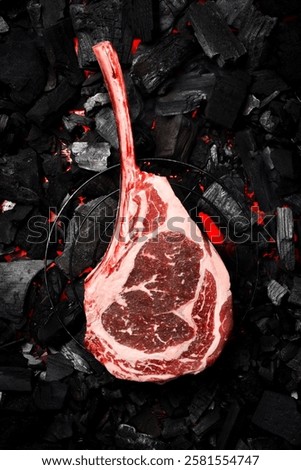 A raw aged Tomahawk steak is grilled over hot coals. Barbecue. Top view.
