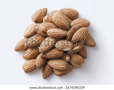 Raw almonds with shells piled together on a clean white surface close-up natural texture detail healthy snack ingredient
