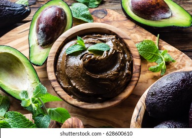 Raw Avocado Chocolate Mousse Pudding With Mint In Olive Wooden Bowl. Vegan Vegetarian Food. Organic Healthy Dessert. Top View