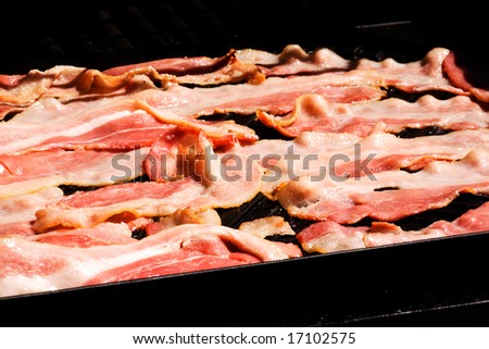 Raw bacon being grilled on an open grittle