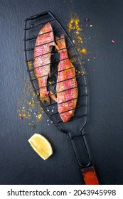 Raw barbecue red mullet with spice and lemon slice offered in a fish grillage as top view on black background  - Shutterstock ID 2043945998