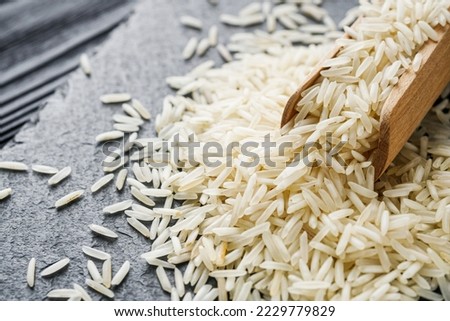 raw basmati rice on a black wooden background.