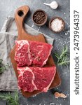 Raw beef chops on a cutting board. Animal product, red meat vertical photo