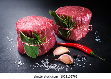 Raw beef fillet steaks mignon with spices on dark background