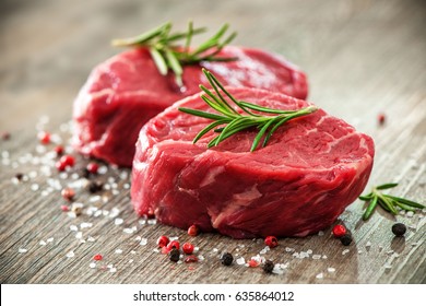 Raw beef fillet steaks with spices on wooden background