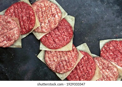 Raw Beef Hamburger Patties On Paper And Black Background, Overhead View. Raw Burger Cutlets On Isolated Background, Top View. Many Raw Minced Steak Burgers From Beef Pork Meat On Black Background.