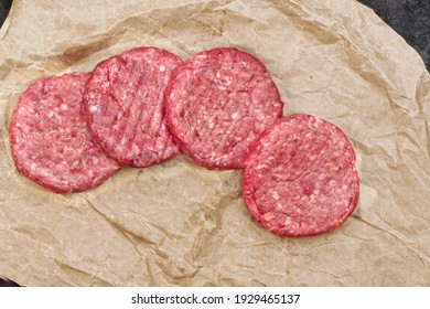 Raw Beef Hamburger Patties On Paper And Black Background, Overhead View. Raw Burger Cutlets On Isolated Background, Top View. Many Raw Minced Steak Burgers From Beef Pork Meat On Black Background.