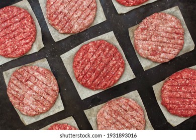 Raw Beef Hamburger Patties On Paper And Black Background, Overhead View. Raw Burger Cutlets On Isolated Background, Top View. Many Raw Minced Steak Burgers From Beef Pork Meat On Black Background.