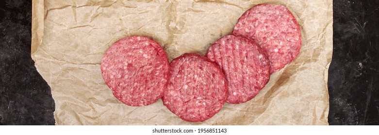 Raw Beef Hamburger Patties On Paper And Black Background, Overhead View. Raw Burger Cutlets On Isolated Background, Top View. Many Raw Minced Steak Burgers From Beef Pork Meat On Black Background.