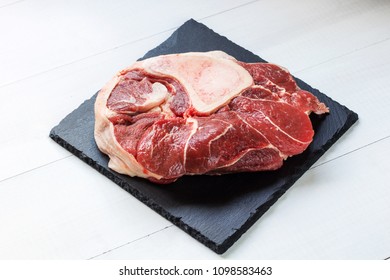 raw beef meat with bone on black stone plate