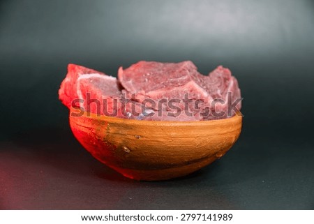 Raw beef meat chunks in a clay bowl on a dark background fresh red meat pieces for cooking, high protein food, culinary ingredient for beef stew or steak
