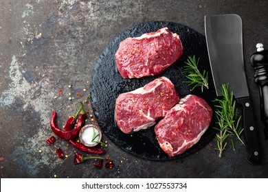 Raw Beef Meat. Fresh Steaks On Slate Board On Black Background. Top View