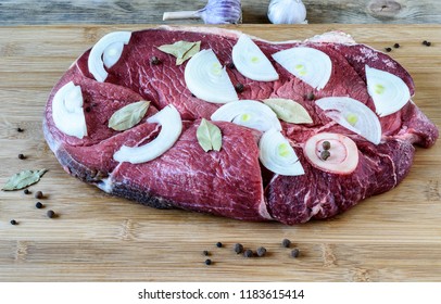 Raw beef meat with laurel leaves, black peppercorns and onion slices on a cutting board - Shutterstock ID 1183615414