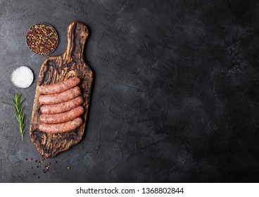 Raw Beef And Pork Sausage On Vintage Chopping Board With Salt And Pepper On Black Background.