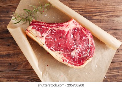 Raw Beef Rib Steak With Bone On Wooden Board And Table