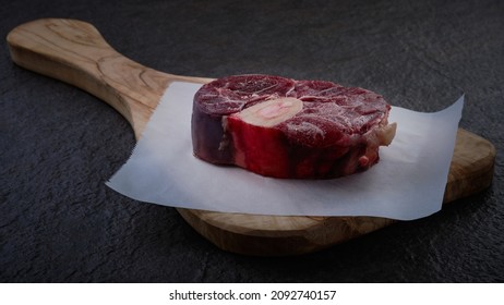 Raw beef shank ready for cooking. Fresh raw osso buco veal shank on baking paper. Fresh beef cut on wooden cutting board