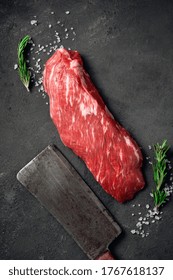 Raw Beef Shoulder Tenderloin Steak With Salt And A Meat Cleaver On A Dark Stone Background