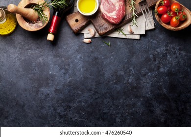 Raw beef steak cooking and ingredients. Meat piece, red wine, herbs and spices. Top view with copy space over stone table - Powered by Shutterstock